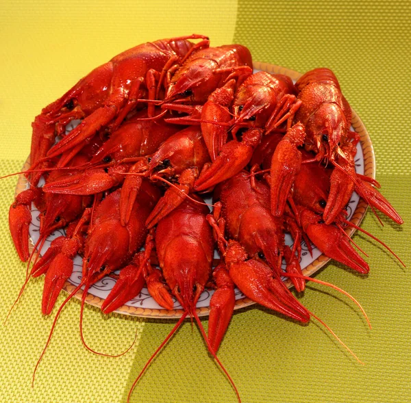 Boiled crawfish on a plate on a green background.