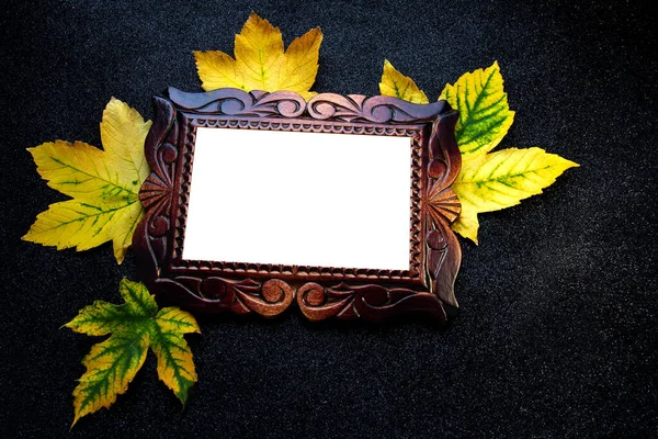 Autumn wooden frame. Carved frame on a black background with leaves.