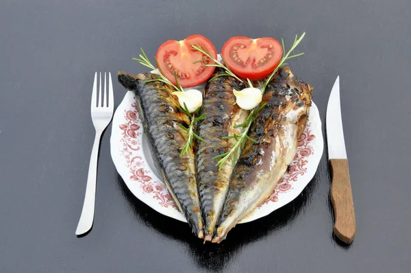 Domates ve soğan ile beyaz bir tabak ızgara balık.