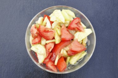 bir tabak salata salatalık ve domates gri bir arka plan üzerinde