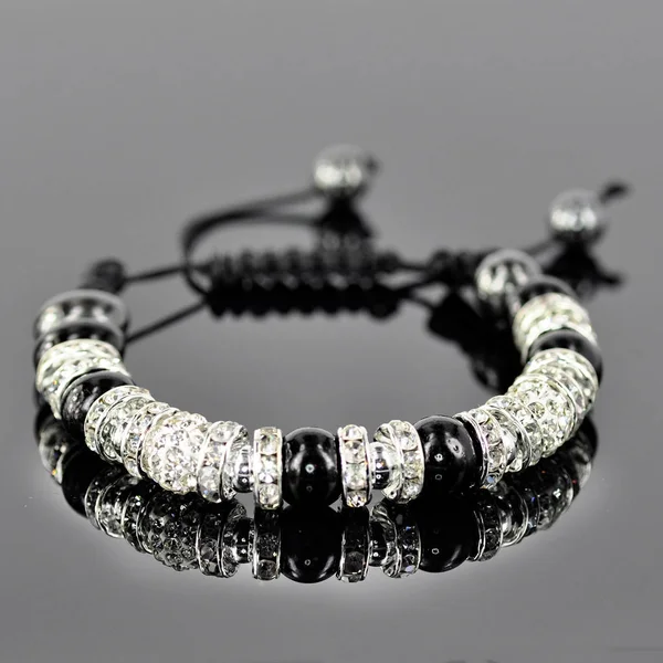 Style bracelet en argent avec des charmes blancs isolés sur verre noir — Photo