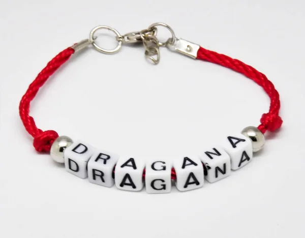 Modern bracelet with names on a red braid on a white background — Stock Photo, Image