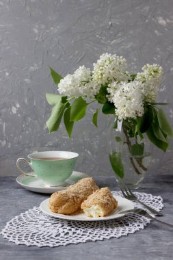 Bir fincan çay, bir demet leylak desenli nefis ekler..