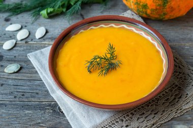 Kırsal ahşap arka planda dereotlu balkabağı çorbası..