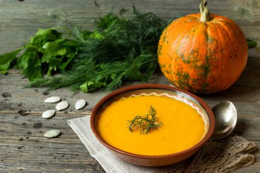 Kırsal ahşap arka planda dereotlu balkabağı çorbası..