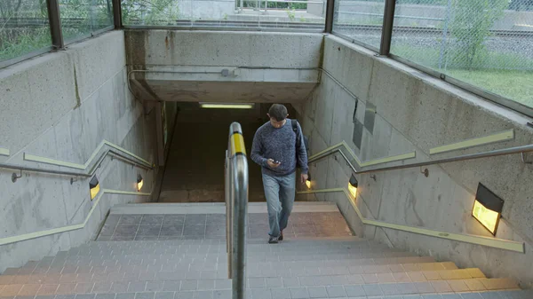 年轻人爬上车站的楼梯 手里拿着手机 背上背着背包 一个人在火车 公共汽车 地铁的飞机上赶时间 在车站上赶车 — 图库照片