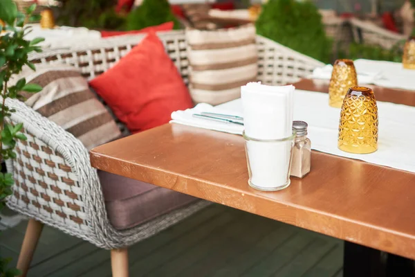 Summer terrace veranda of the cafe. Cozy gray wicker chairs with cushions, served tables and green bushes — Stock Photo, Image