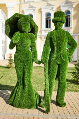 Astrakhan, Rusya - 09.18.2020: Şemsiyeli ve parlak etekli bayanın tespih heykeli ve baston ve silindir şapkalı Jentleman