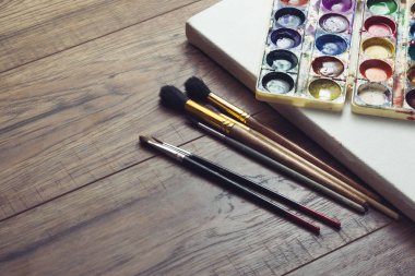 paint brushes and watercolors on wooden background clipart