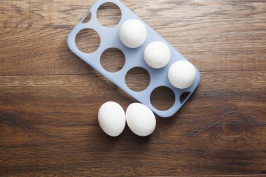 ahşap masa üzerinde birçok beyaz yumurta