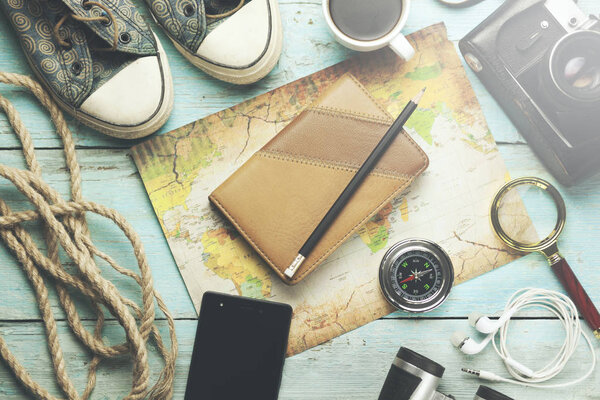 Things of traveler on the wooden background. Shoes, camera, smartphone, compass, notepad, map