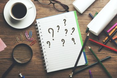 Masa üstünde bir defter üzerinde soru işaretleri