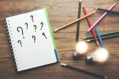 Masa üstünde bir defter üzerinde soru işaretleri
