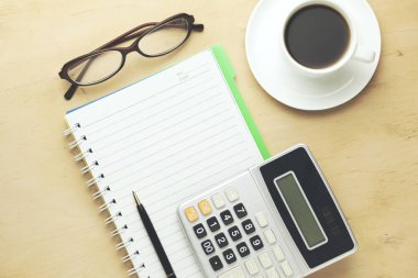 Fincan kahve, defter, hesap makinesi ve ahşap zemin üzerine kalem