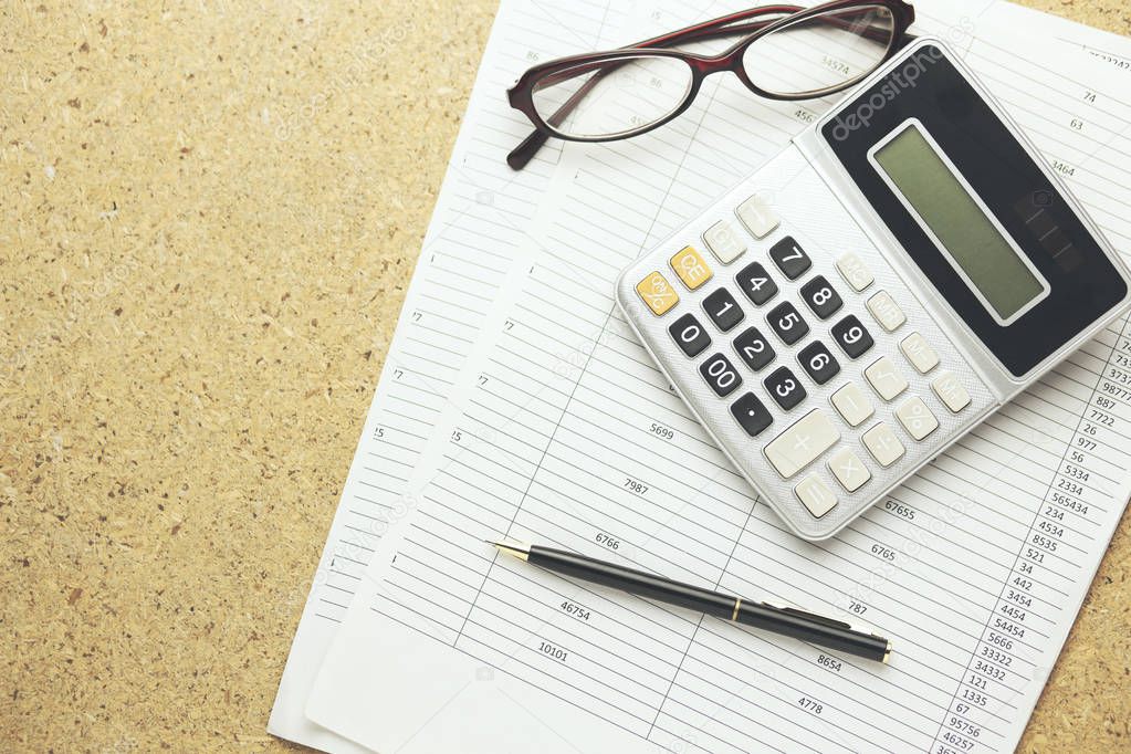 calculator, glasses and pen on documents on table