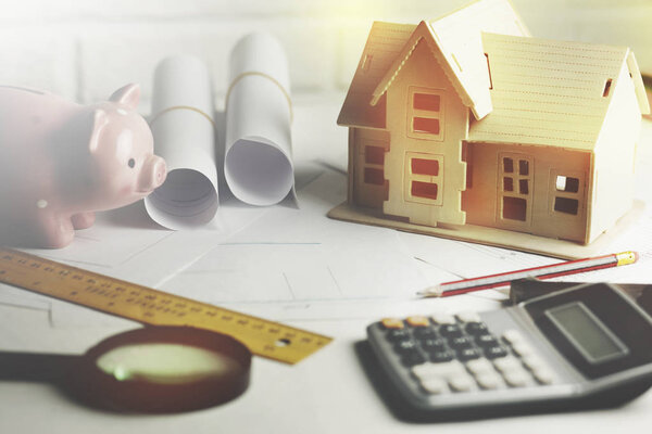 house model with calculator and piggy bank on table