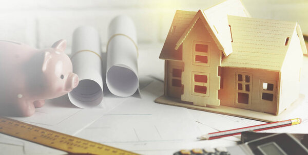 house model with calculator and piggy bank on table