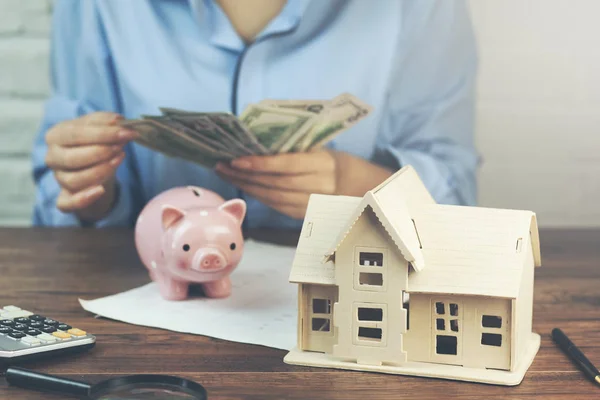 Vrouw Met Geld Met Huis Model Piggy Bank Tafel — Stockfoto