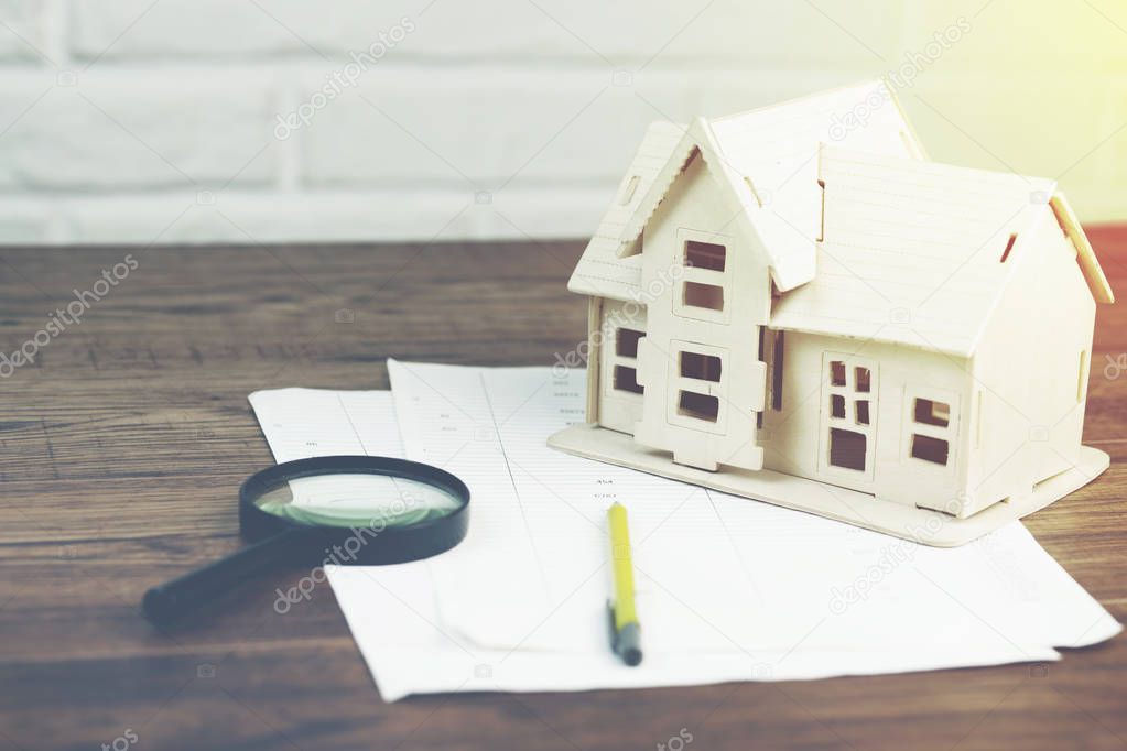 house model with magnifier on documents on table