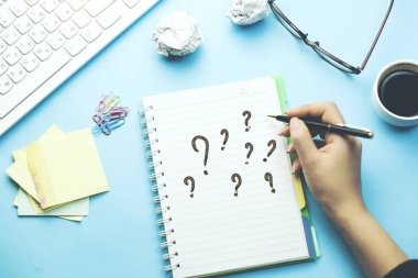 kadın notepad ile masa üstünde klavye üzerinde soru işaretleri yazmıştır