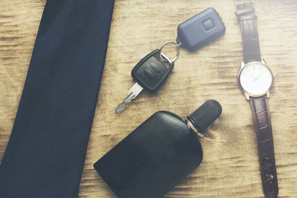 Men accessories:perfume,tie,watch and key on table