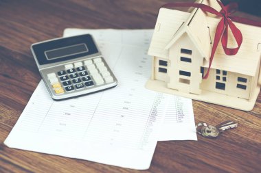 ev modeli ile hesap makinesi ve belgeler üzerinde ahşap arka plan üzerinde anahtar