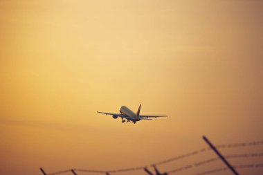 Silhouette uçak ve turuncu gökyüzü günbatımı, çit