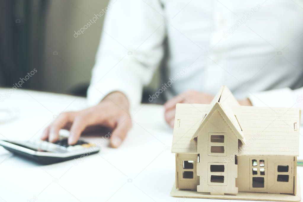 Male hands, house model and calculator on table