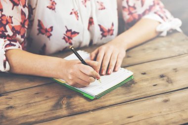 Not defterine kalem yazan kadın eller