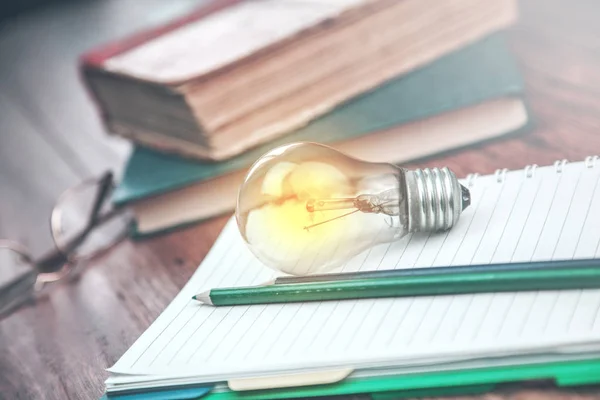 idea light bulb on notepad with  books on table