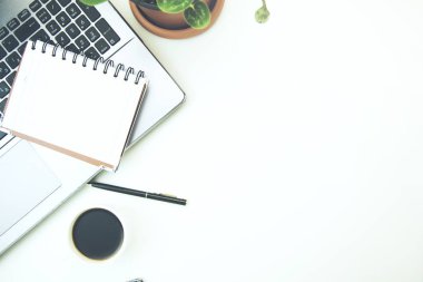 Not defteri, bilgisayar ve kahve fincanı olan ofis masası.