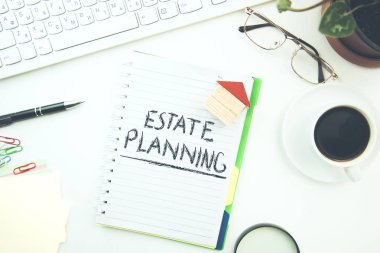 Ofis masasında Not defteri ve ev modelinde Emlak planlama metni