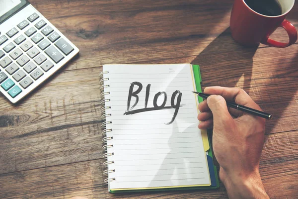 man written blog text on notepad with calculator and coffee on table