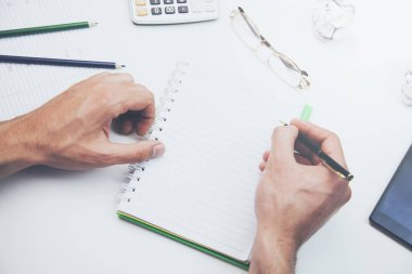 adam el not defteri ve kalem masada çalışıyor