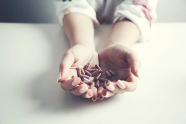 Kadın eli bir sürü hap tutuyor.