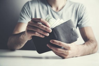 Genç adam cüzdana para sayıyor.