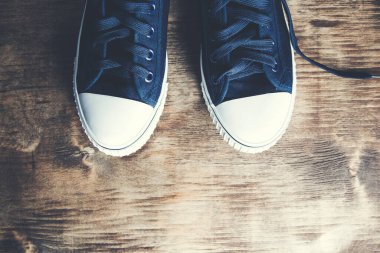 Ahşap masada bir çift spor ayakkabı.