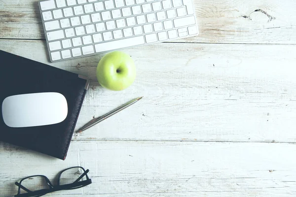 Keyboard with notepad and apple on desk