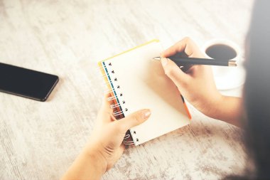 Kadın el bilgisayarı ve masada kahve olan bir telefon.