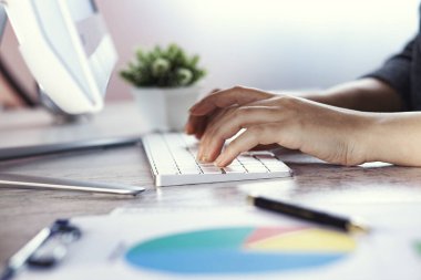 Kadın el klavyesi ve grafiği masaya.