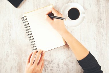 Kadın el bilgisayarı ve masada kahve olan bir telefon.