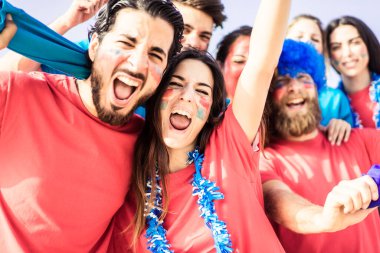 Futbol fanatiği bağırıyor, stadyumun içinde kırmızı gömlekler var. Bir grup genç futbol için çok heyecanlı. Spor ve eğlence kavramı - Görüntü