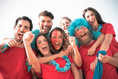 Futbol fanatiği bağırıyor, stadyumun içinde kırmızı gömlekler var. Bir grup genç futbol için çok heyecanlı. Spor ve eğlence kavramı - Görüntü