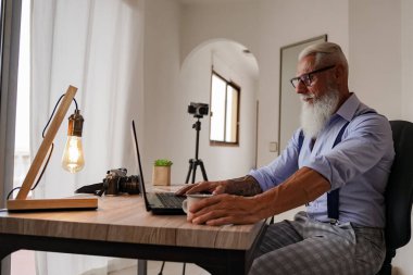 Stüdyoda dizüstü bilgisayarı üzerinde çalışan yaşlı bir adamın görüntüsü, iş adamının elleri ofis masasında dizüstü bilgisayarla meşgul, erkek bilgisayarda daktilo ediyor ve iyi ekspres kahve içiyor. Odaklan. Resim