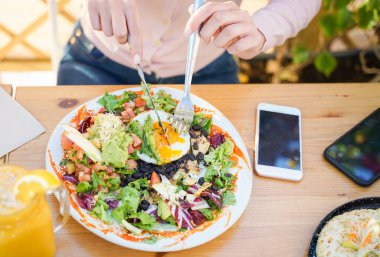 Restoranda yumurtalı vejetaryen salatası yiyen bir kadın. Yumurtalı salata, ekmek ve domates. Beyaz bir tabaktan yemek yemek. Yemek ve diyet konsepti - Görüntü
