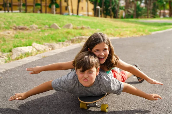 哥哥和姐姐玩滑板 在公园里玩长板滑板的小男孩和小女孩 夏天的时候还年轻家庭和童年的概念 把脸集中起来图像 — 图库照片