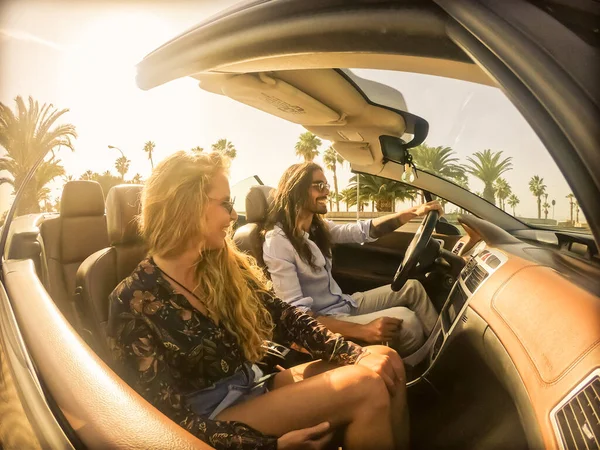 Happy young couple having fun inside convertible sport car. Woman and man happy with a beautiful sunset. Vacation, journey and relationship concept. Image