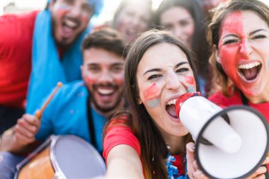Futbol fanatiği bağırıyor, stadyumun dışında kırmızı gömlekli. Bir grup genç futbol için çok heyecanlı. Spor ve eğlence kavramı - Görüntü