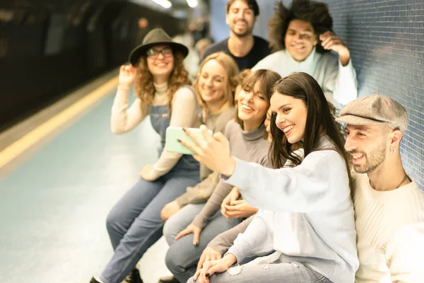 Bir grup arkadaş metro istasyonunda cep telefonunu selfie çekmek için kullanıyor. Gülümseyen insanlar bir sonraki treni bekliyor ve cep telefonuyla oynuyorlar. Teknoloji bağımlılığı olan insanlar kavramı - görüntü