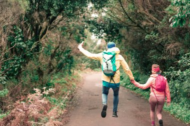 Genç insanlar yüksek dağ yürüyüşleri yapıyor. Yürüyüşçüler güzel bir günde çok mutlu olurlar. Adam mutlu bir şekilde atlıyor. Hayatta kalma, seyahat ve macera yaşam tarzı kavramı. Resim